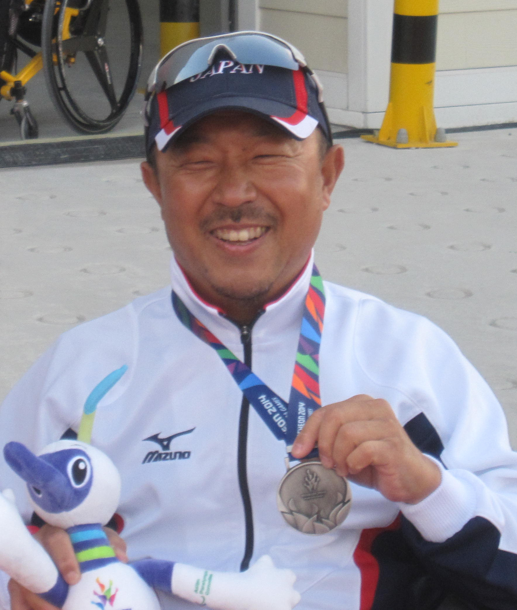 写真：アジア大会の銀メダルとマスコットを手にした山本真也が記念撮影している様子