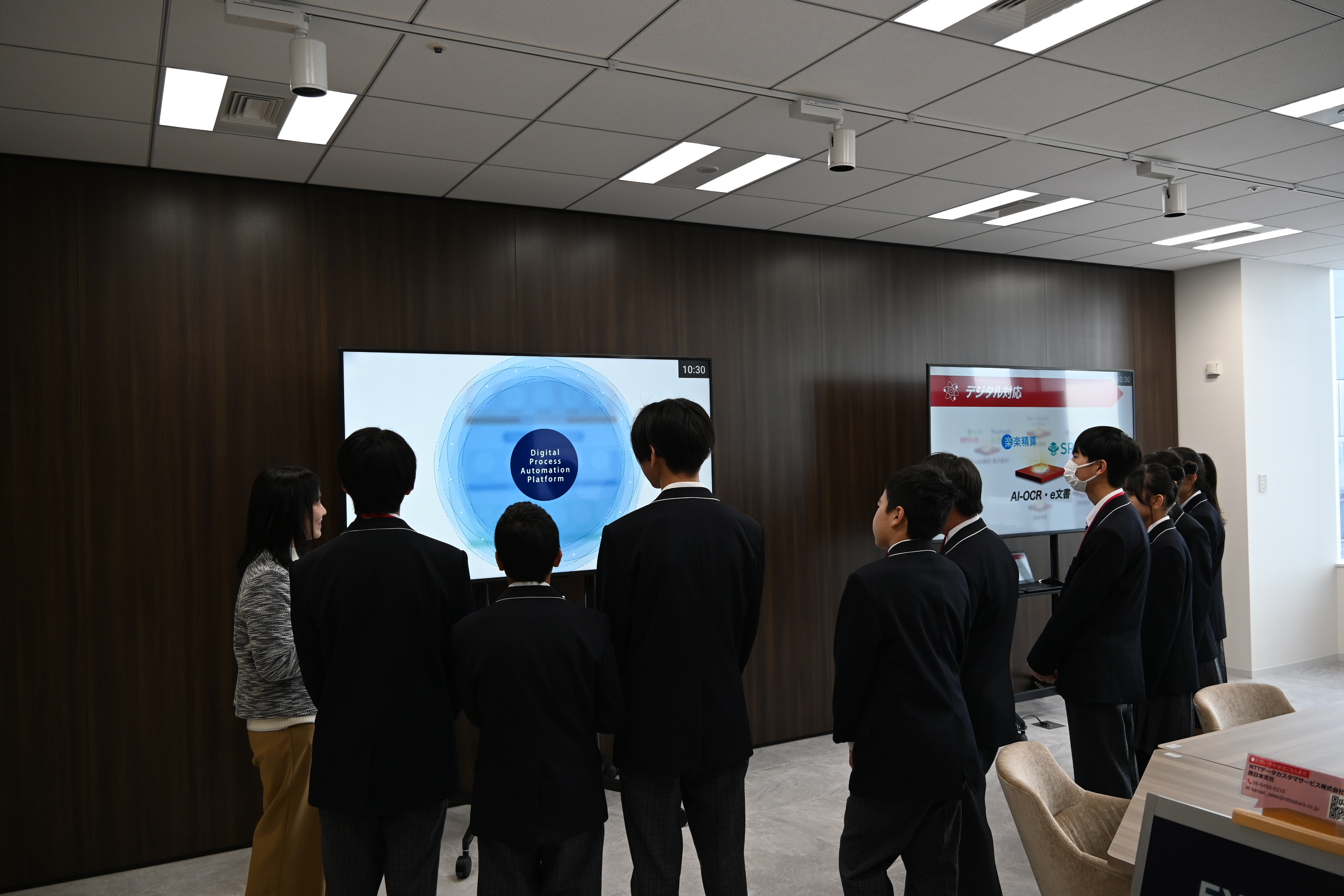 写真：生徒のグループがモニターの映像を見ながら案内を受けている様子